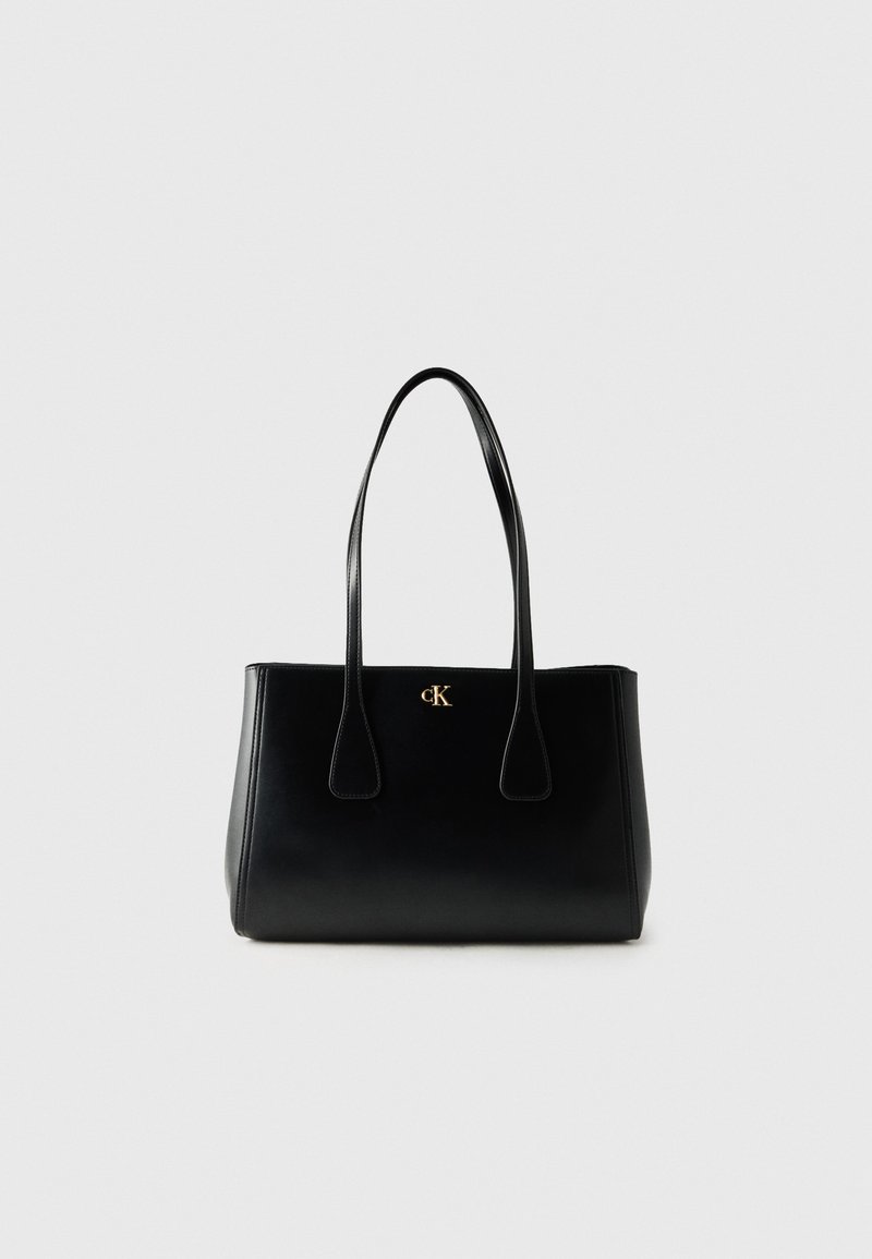 Sac cabas en cuir noir avec deux longues poignées et petit logo doré « cK » au centre devant.