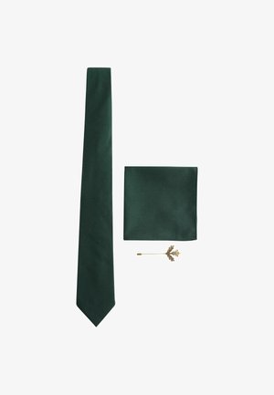 Dark green tie with a subtle ribbed texture, matching pocket square, and a gold lapel pin shaped like a leaf.