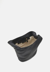 Musta nahkakäsilaukku, jossa on pehmeä, tekstuuriltaan ainutlaatuinen ulkopinta, avoin yläosa ja beige vuori. Mukana on vetoketjullinen tasku ja brändättyä metalliosaa sisäpuolella.