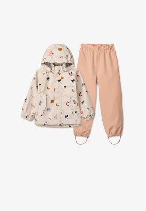 Veste de pluie beige clair avec des motifs ludiques, y compris des chats et des nœuds, associée à un pantalon imperméable couleur saumon. Comprend des poignets élastiques et des poches.