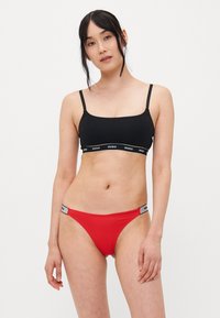 Zwarte bralette met dunne bandjes en HUGO logo band; rode bikini onderkant met HUGO logo tailleband; gladde stof, aansluitend ontwerp.