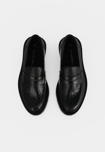 Ζευγάρι μαύρα πλεκτά δερμάτινα loafers με στρογγυλεμένες μύτες και οριζόντια λωρίδα, τοποθετημένα δίπλα-δίπλα πάνω σε λευκό φόντο.