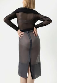 Schwarzes, durchsichtiges Langarmtop aus strukturiertem Stoff, kombiniert mit einem durchsichtigen grauen Rock mit einem Schlitz hinten und Satinakzenten.