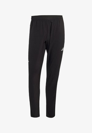 Czarne spodnie sportowe z elastycznym pasem, zwężane na kostkach, z małym białym logo Adidas na górnej części uda.