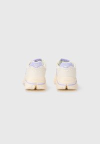 Light-colored sneakers with a round shape, featuring a textured cream upper, lavender accents, and Vibram label on the heel.