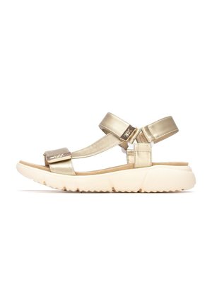 Sandalias metálicas doradas con dos correas ajustables, una suela acolchada y una suela exterior de goma blanca texturizada. Vista lateral que muestra el diseño y el material.