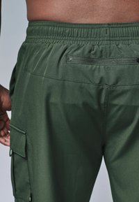 Grønne cargobukser med elastisk talje, der har en lynlåslukket baglomme og sidetasker, i en glat, mat finish.