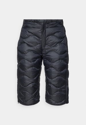 Mustat eristetyt tikatut polvimittaiset shortsit, joissa on etuvetoketju ja aaltojen muotoista tikkausta, suunniteltu kylmille sääolosuhteille.