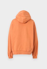 Hoodie u narančastoj boji, izrađen od mekanog materijala, ima širok kroj, rebraste manžete i jednostavan dizajn na leđima bez ukrasa.