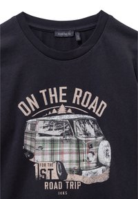 Zwarte katoenen t-shirt met een grafische print van een bestelwagen in een ruitpatroon, met de tekst "ON THE ROAD" en "1st ROAD TRIP" in beige.