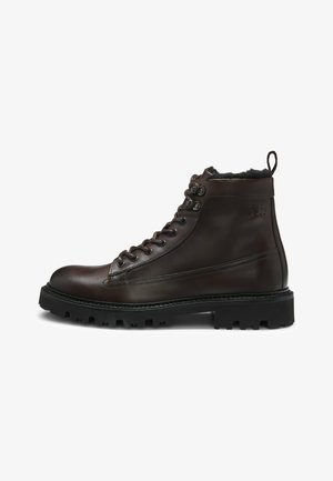 Stivali alla caviglia in pelle marrone con lacci, punta rotonda, suola in gomma e finitura texture. Presenta un cordino a cappio sul retro.