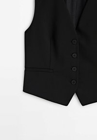 Gilet formel noir avec quatre boutons sur le devant et une petite poche passepoilée sur le bas à gauche.