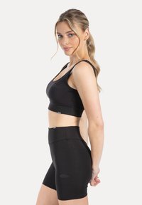 Zwarte sportbeha en shorts met hoge taille van rekbare stof. De beha heeft een ronde halslijn, en beide stukken hebben subtiele branding.