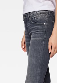 Mörkgrå denimjeans med slim fit, med fem fickor, dragkedja fram och subtila slitningar över låren.