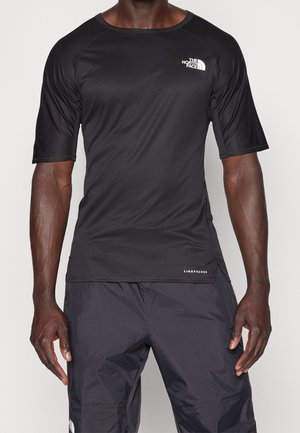 Homme portant un t-shirt de sport noir moulant à manches courtes et un pantalon léger noir, tous deux avec le logo The North Face.