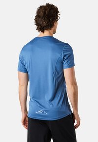 Blå kortärmad sporttröja i mjukt material, med rundad halsringning och en vit bergslogotyp på nedre delen av ryggen.