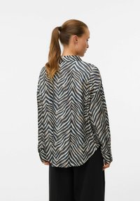 Langermet skjorte i et lett materiale, med et dristig marineblått og beige zebra-mønster, samt buet kant og avslappet passform.