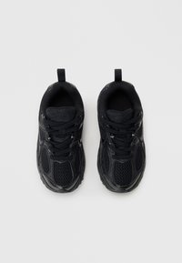 Chaussures de sport noires avec une tige en mesh, des panneaux latéraux texturés et une semelle en caoutchouc. Comprend des lacets et des languettes pour un enfilage facile.