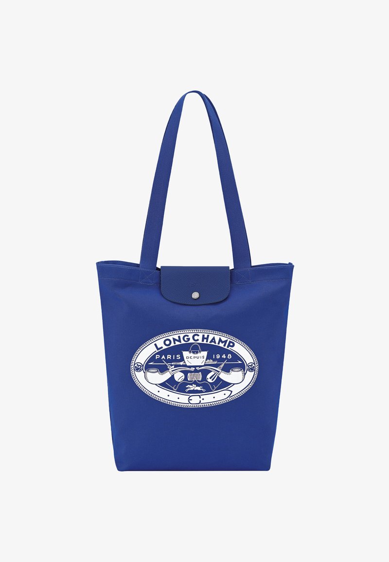Blue tote bag made of durable fabric featuring a white logo design with "LONGCHAMP PARIS DEPUIS 1948" and an embossed button closure.