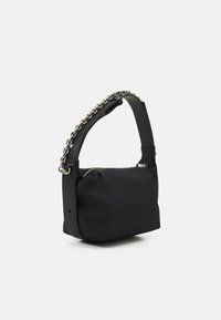 Svart handväska med en strukturerad nylonkropp och ett kontrasterande metallkedjestropp. Har en dragkedjestängning och rundad form.