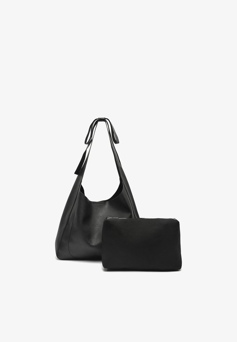 Czarna skórzana torba typu tote z długimi uchwytami obok mniejszej prostokątnej czarnej saszetki na suwak na białym tle.