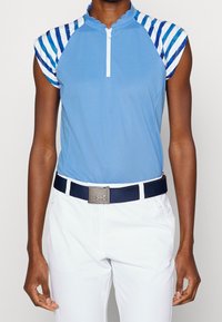 Ljusblå polo skjorta med scallopad krage, färgglada randiga ärmar, ihop med vita byxor och ett marinblått bälte med en silverspänne.