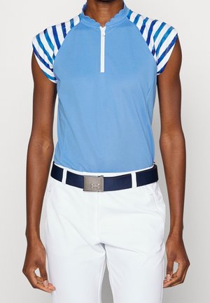 Polo bleu clair avec un col festonné, des manches rayées colorées, associé à un pantalon blanc et une ceinture bleu marine avec une boucle en argent.