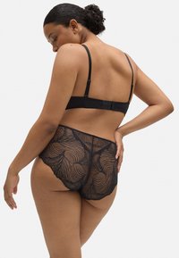 Conjuntos de lencería de encaje negro con intrincados patrones en forma de pluma, tirantes ajustables y un cierre de gancho en la parte posterior.