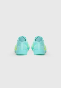 Light teal athletic shoes with a mesh upper, reinforced heel, lime green accents, and a textured outsole. The design is low-profile and streamlined.