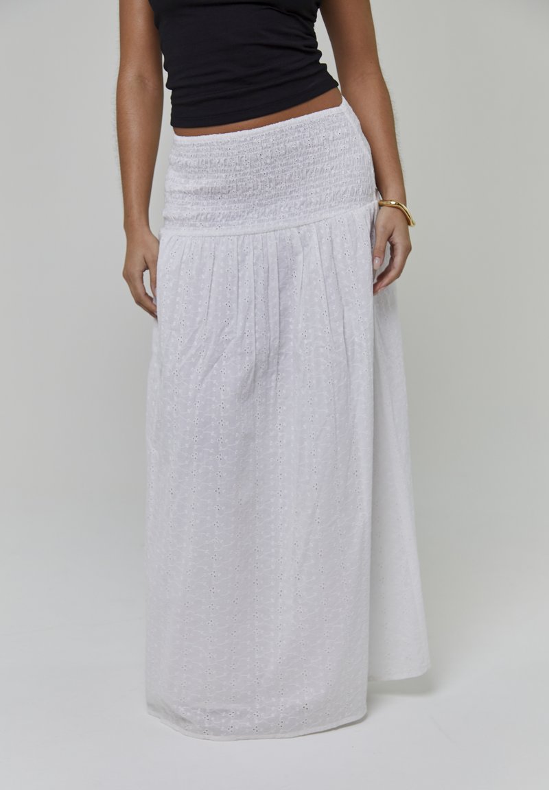 Gonna lunga bianca in tessuto leggero con vita arricciata, caratterizzata da un ricamo floreale sottile su tutta la superficie e una silhouette fluida.