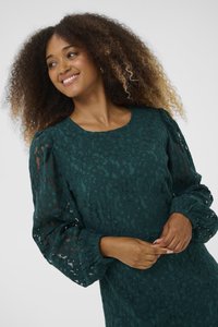 Lace dress in deep green with floral pattern, round neckline, and puffed long sleeves; textured fabric adds depth to the design.
