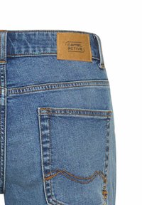 Spijkerbroek in lichtblauwe kleur, met een leren label "camel active" op de tailleband en standaard achterzakken.