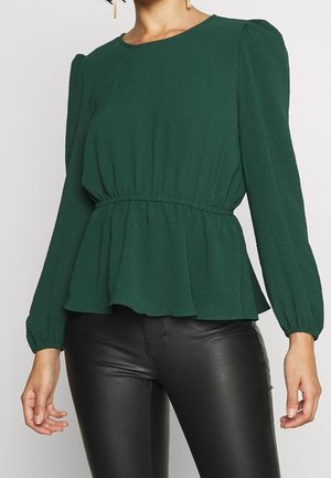 Groen peplumtop met lange pofmouwen, ronde hals, gestructureerde stof en elastische tailleband, gecombineerd met zwarte legging.