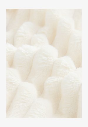 Teksturēts krēmkrāsas plīša audums ar paceltām, viļņotām rakstu līnijām. Mīksta, pūkaina virsma uzlabo taustes pieredzi, piemērots segām vai mēbeļu apdarēm.