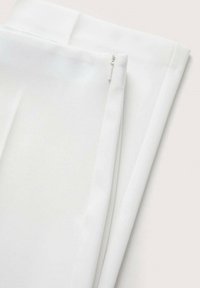 Tissu blanc avec une texture lisse et une fermeture éclair dissimulée. Pliée soigneusement, mettant en valeur des bords nets et un design minimaliste.