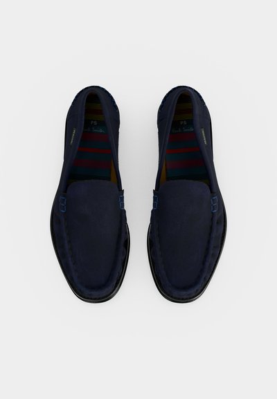 Μπλε σκούρα σουέτ μοκασίνια με στρογγυλεμένα δάχτυλα και ραμμένες λεπτομέρειες, που εμφανίζουν ριγέ πολύχρωμες εσωτερικές σόλες και μαύρες εξωτερικές σόλες, εμφανιζόμενα από πάνω.