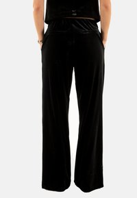 Pantalons larges noirs en velours. Caractéristiques d'une texture lisse, d'une taille élastique et de poches latérales. Design simple et classique.