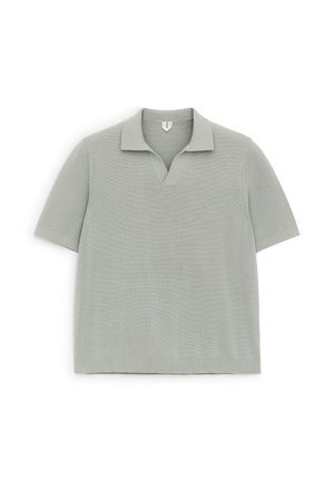 Helehall lühikeste varrukatega kootud polo särk V-kujulise kaelusega, laotatud valgele taustale.