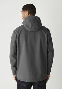 Grey waterproof jacket with a hood, featuring a smooth texture, adjustable collar, and simple design. Worn over dark jeans.