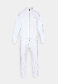 White tracksuit made from smooth, lightweight material. Features a zip-up jacket with a high collar and elastic cuffs, and matching elastic waist pants.