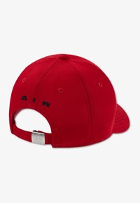 Κόκκινο καπέλο μπέιζμπολ με καμπυλωτό γείσο, φτιαγμένο από ύφασμα. Διαθέτει την επιγραφή «AIR» κεντημένη με μαύρα γράμματα στο πίσω μέρος και ασημί λογότυπο στη λουρίδα.