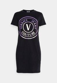 Černé tričkové šaty s velkým, reflexním logem Versace Jeans Couture ve středu. Krátké rukávy a přiléhavý střih.