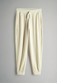 Ljust krämfärgade ribbade joggers med elastisk midja, dragsko och åtsittande manschetter; har två sidofickor.