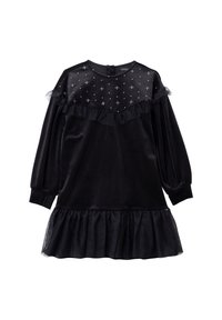 Czarna aksamitna sukienka z przezroczystą górą ozdobioną wzorem gwiazd, z falbanianym kołnierzem i rękawami oraz rozkloszowanym falbanianym dołem. Długie rękawy zakończone elastycznymi mankietami.