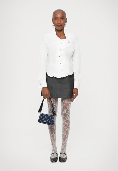 Camicia bianca con bottoni arancioni, mini gonna grigia, collant bianchi a fantasia e scarpe nere. Borsa blu con un design testurizzato.