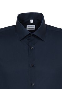Camicia da uomo slim-fit blu navy realizzata in tessuto liscio, con colletto a punta e bottoni neri sul fronte. Etichetta del marchio visibile all'interno.