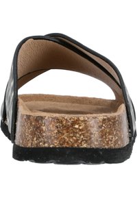Svart och vit mönstrad sandal med en korkmellansula, texturerad brun innersula och en flexibel remdesign. Solid svart yttersula.