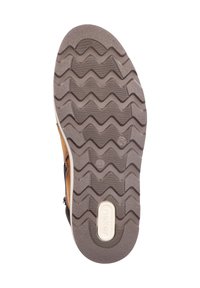 Zool van een schoen met een textuur in een zigzagpatroon van bruin rubber, met een crème logo in het midden en een versterkte rand voor duurzaamheid.