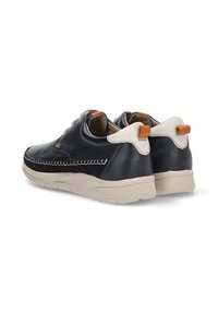 Zapatillas de cuero negro con acentos beige, que presentan un diseño cosido, una lengüeta trasera y una suela de goma. Punta redondeada y perfil bajo.