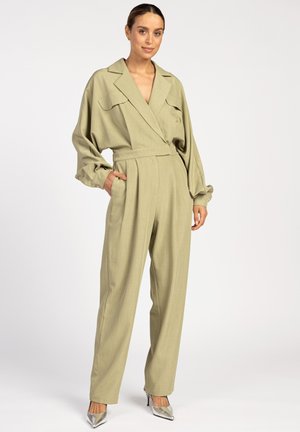 Combinaison vert clair au design cintré, avec des manches larges et une taille ceinturée. Elle comporte deux poches avant et est accompagnée de talons métalliques.